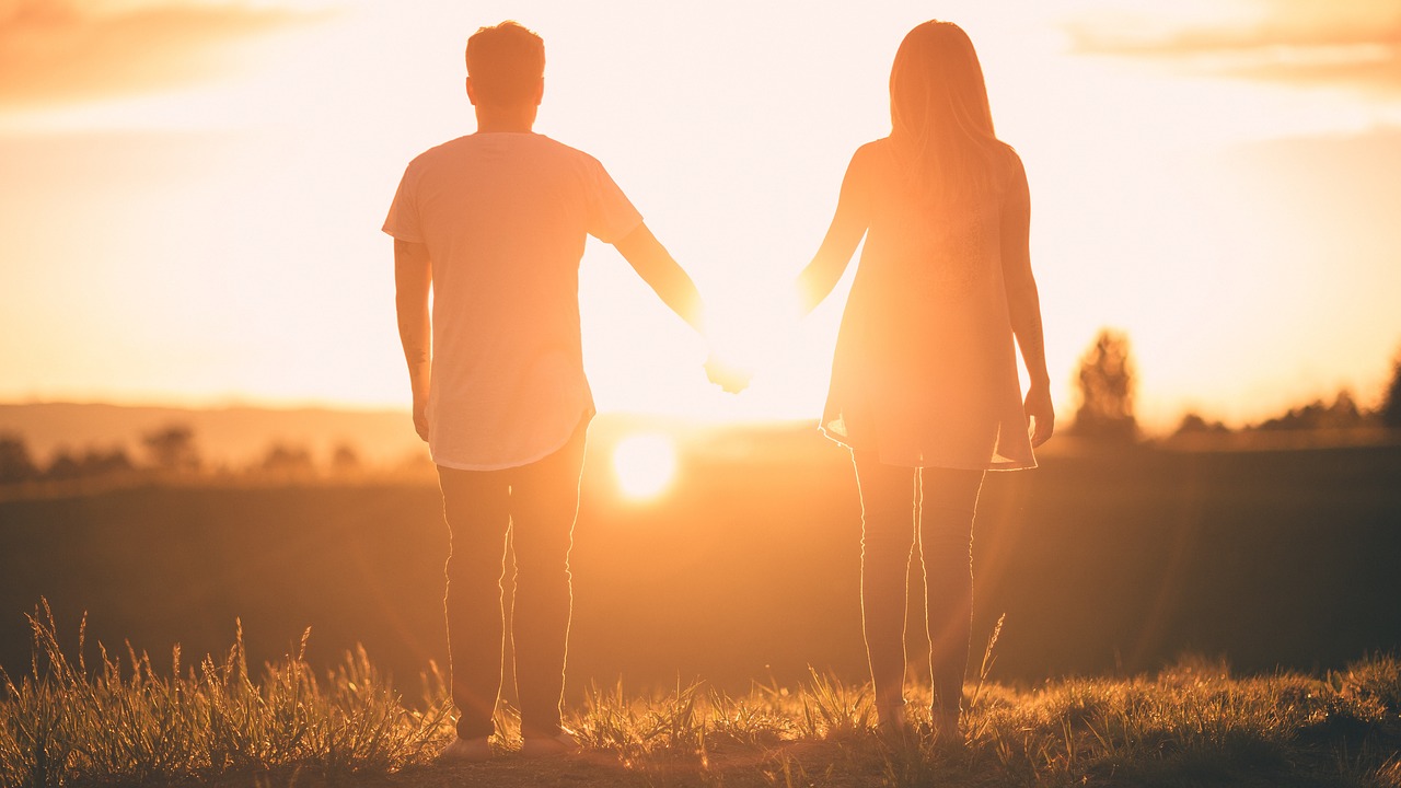 Ein Paar hält Händchen vor einem Sonnenuntergang