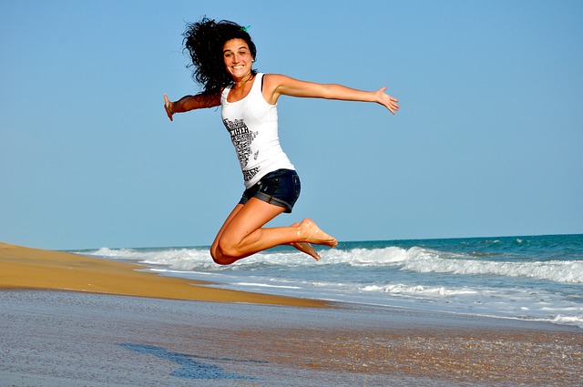 Springende, fröhliche Frau am Strand