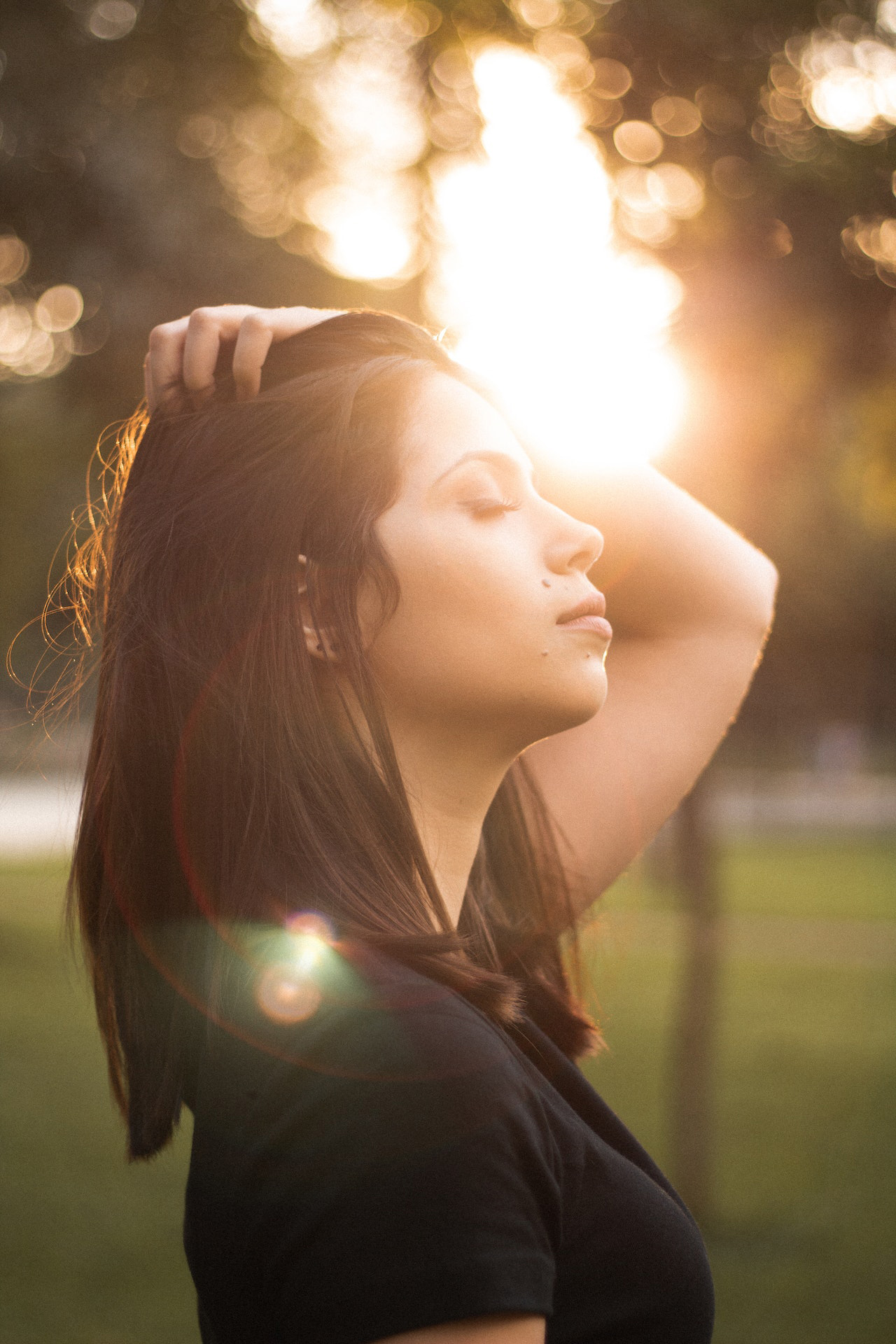 Entspannte Frau im Sonnenlicht mit geschlossenen Augen