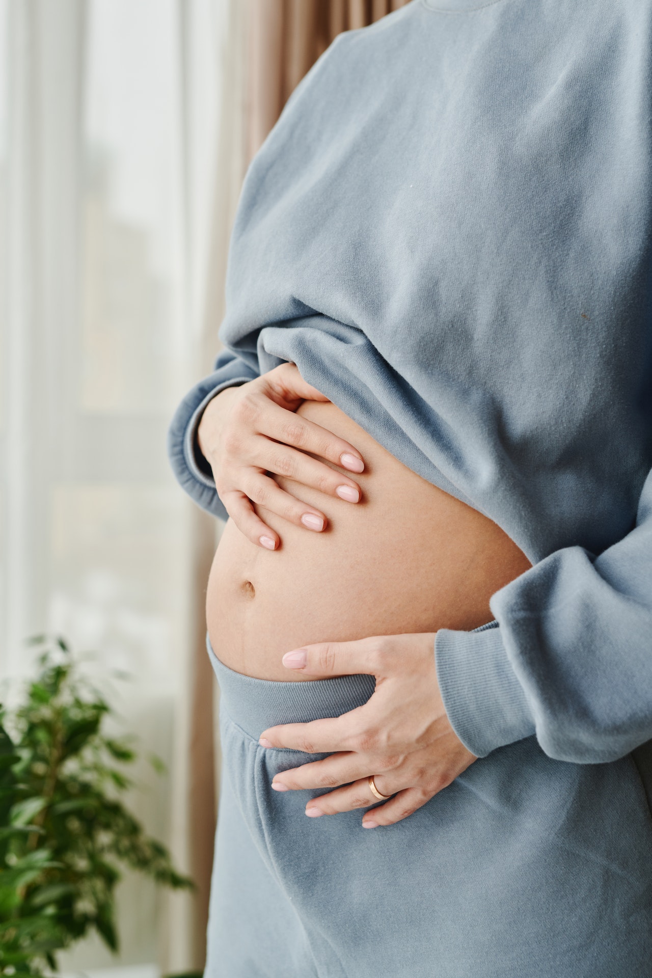 Bauch einer stehenden Person, die ihre Hände daran legt