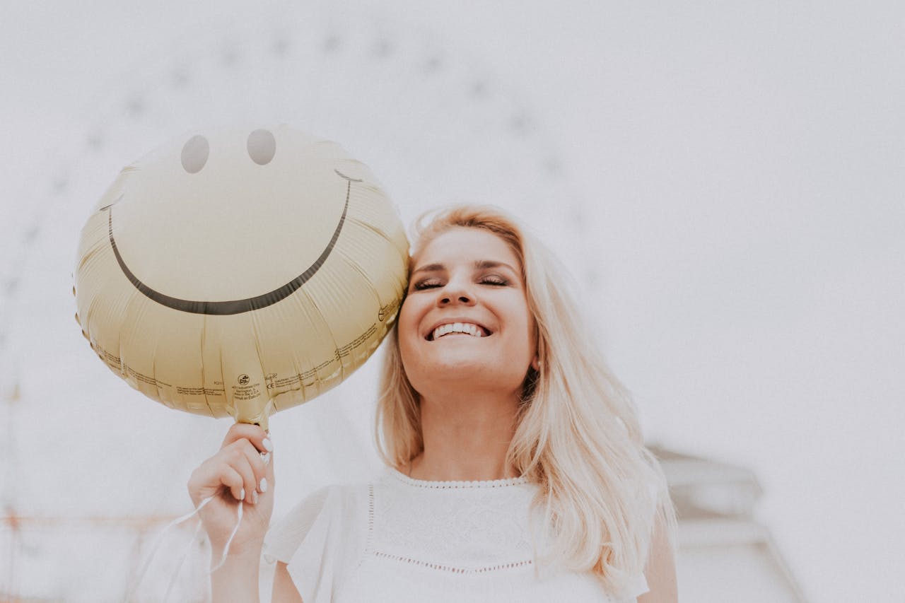 Frau mit Smiley-Luftballon lächelt